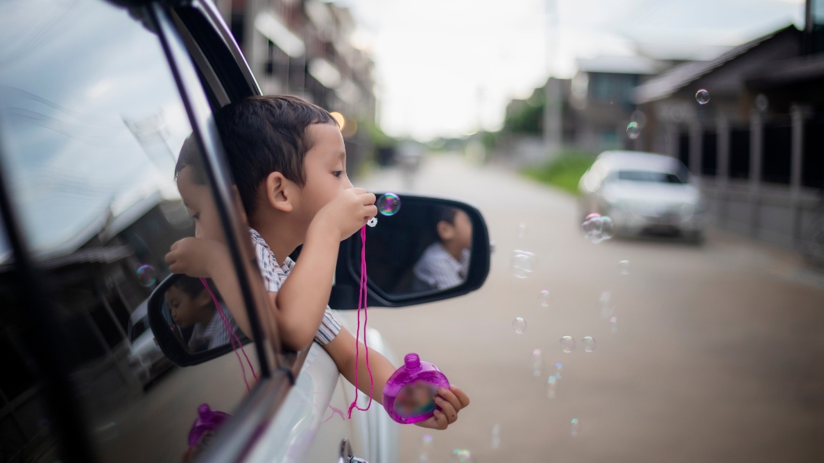 Enfant qui fait des bulles de savon à la fenêtre d'une voiture